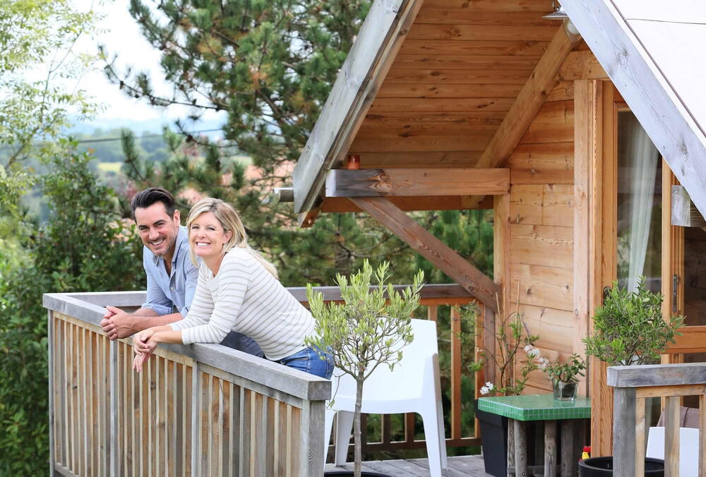 Pärchen grinsend auf einem Balkon einer Blockhütte