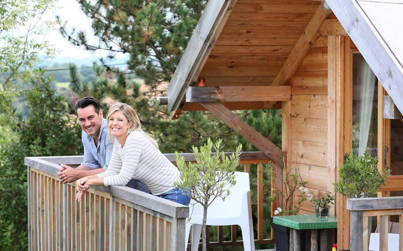 Pärchen grinsend auf einem Balkon einer Blockhütte