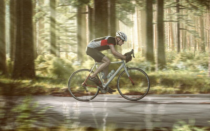 Rennradfahrer auf einer Straße im Wald